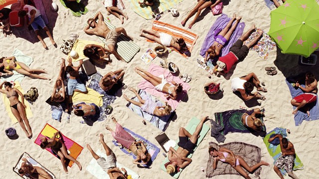 PHOTO: Crowd of people sunbathing on beach.