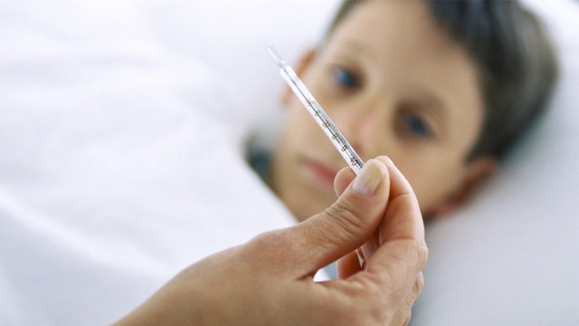PHOTO: Woman taking boy's temperature with thermometer