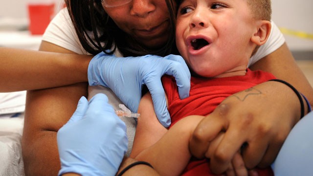 PHOTO: Four-year-old Jovian Ashby-Thomas is held by his mother Cecila while a nurse administers the second of six immunization shots in preparation for entering kindergarten at Coolidge High School in Washington, DC.
