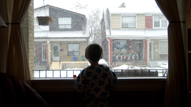 PHOTO: Boy looks out of widow at snow