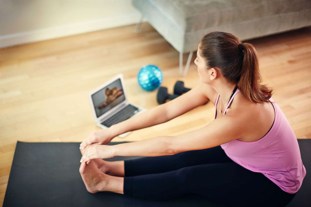 PHOTO: Woman using laptop to exercise at home.