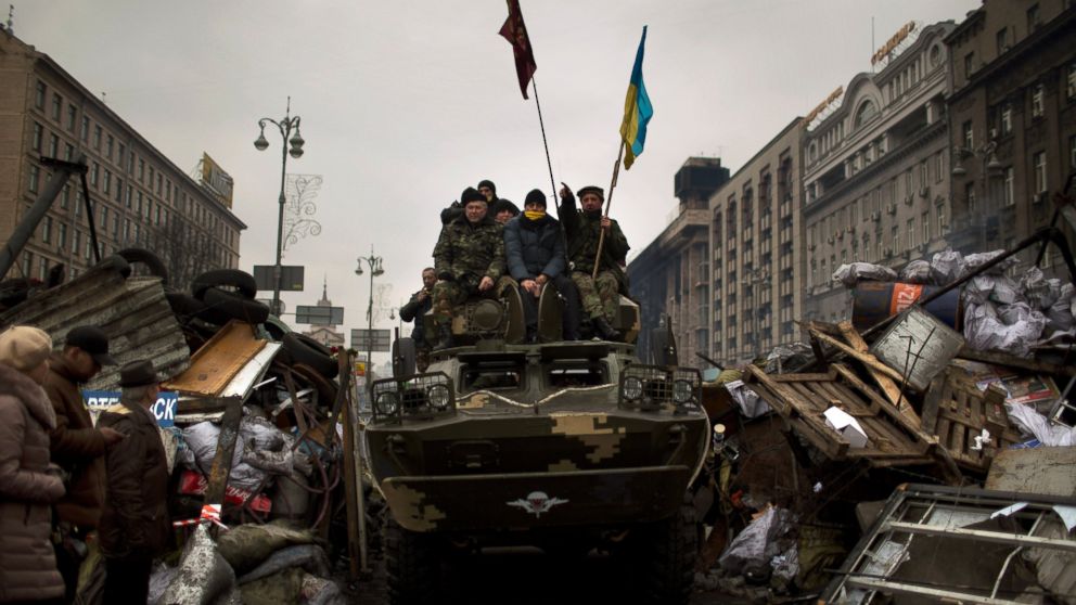 PHOTO: Protesters sit on top of an army armored vehicle along a street in central Kiev, Ukraine, Thursday, Feb. 27, 2014.