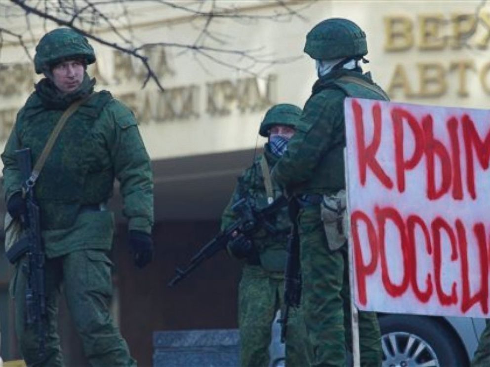 PHOTO: Unidentified gunmen wearing camouflage uniforms block the entrance of the Crimean Parliament building in Simferopol, Ukraine, Saturday, March 1, 2014. Poster reads Crimea Russia.