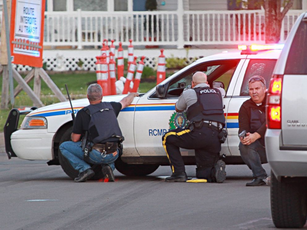 PHOTO: Police officers take cover behind their vehicles in Moncton, New Brunswick, June 4, 2014 following a shooting.