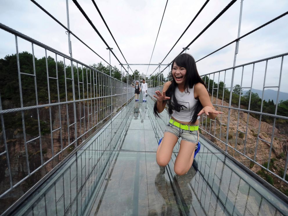PHOTO: A woman plays around as she walks across a glass-bottomed suspension bridge in a scenic zone in Pingjiang county in southern Chinas Hunan province, Sept. 24, 2015.
