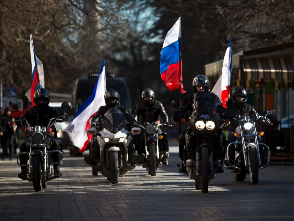 PHOTO: People on motorcycles decorated with Russian and Crimean flags drive in front of a van transporting the coffins of Ukrainian soldiers during their funeral in Simferopol, Crimea, Saturday, March 22, 2014.