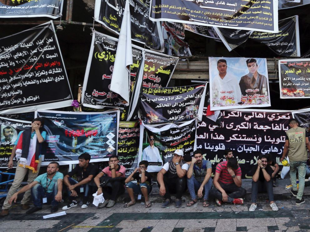 PHOTO: People gather in front of a burned mall covered with posters in memory of the victims at the scene of a massive suicide truck bomb attack in Karada, Iraq, July 10, 2016.