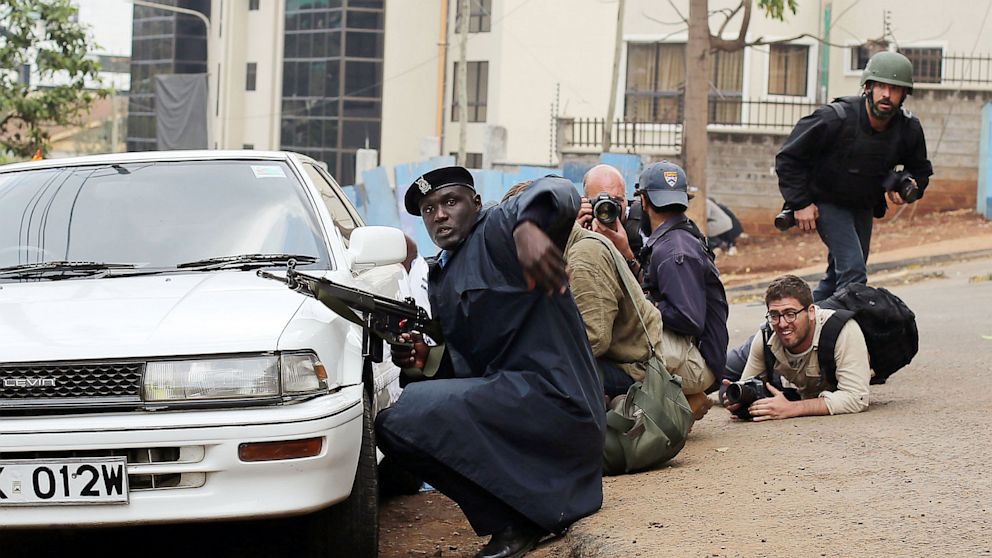PHOTO: Kenyan security personnel and journalists duck behind a vehicle as heavy gunfire erupts from the Westgate Mall in Nairobi Kenya, Sept. 23 2013.