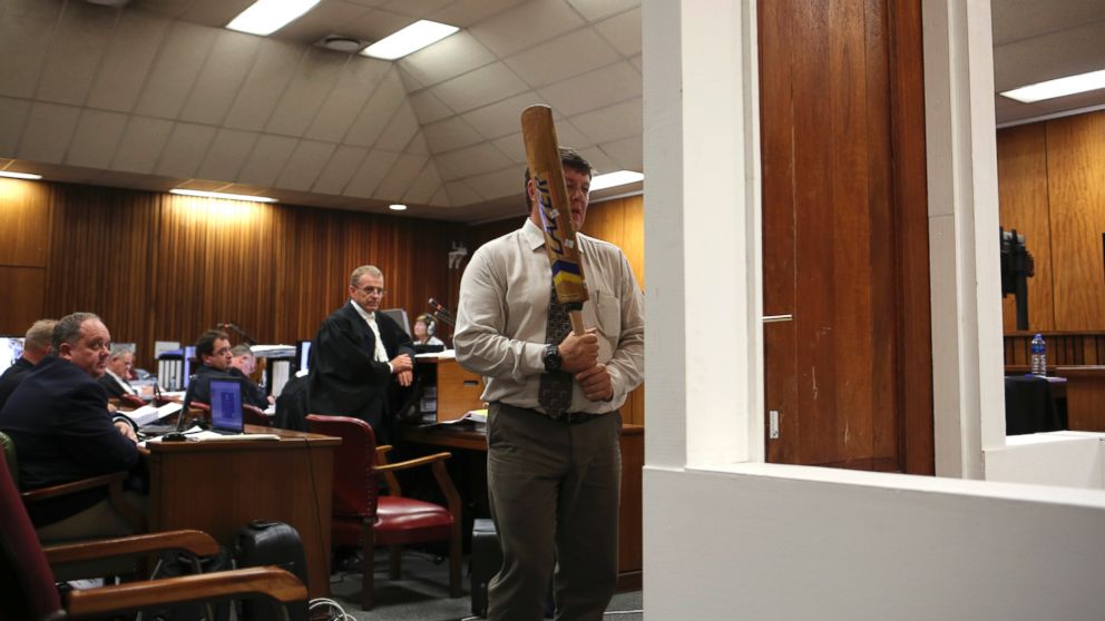 PHOTO: Forensic investigator Johannes Vermeulen is pictured with a cricket bat, demonstrating on a mock-up toilet and door details of how the door could have been broken down, in Pretoria, South Africa on March 12, 2014.