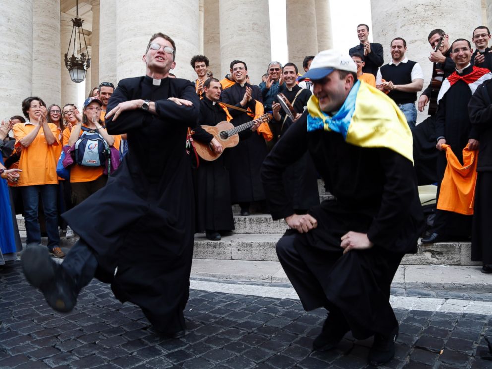 PHOTO: Two priests, one of them with an Ukrainian flag on his shoulders, dance in St. Peters Square at the Vatican, Saturday, April 26, 2014.