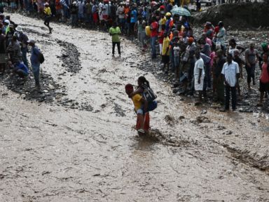 PHOTO: A group of people try to cross the river La Digue, after the colapse of the only bridge that connects to the south after the passing of hurricane Matthew in the country, in Petit Goave, Haiti, Oct. 5, 2016.