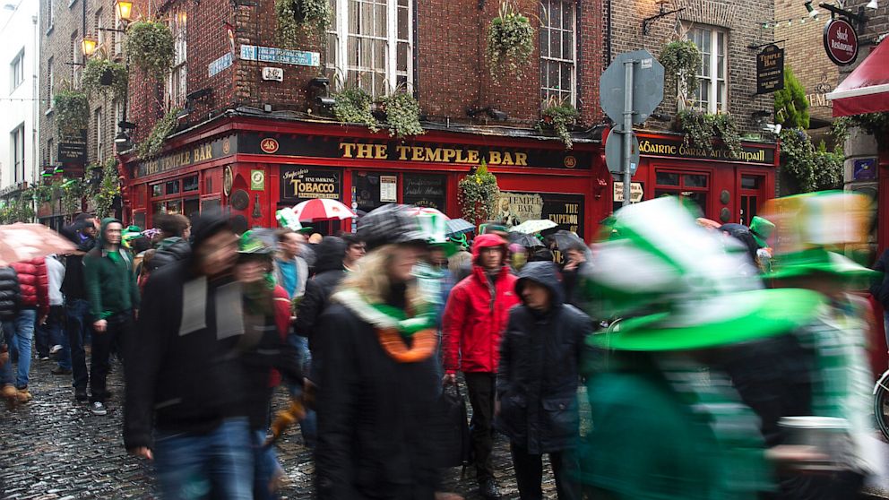 PHOTO: Pedestrians carrying umbrellas and wearing St. Patricks day hats and scarves move past the Temple Bar public house in Dublin, Ireland, March 17, 2013.