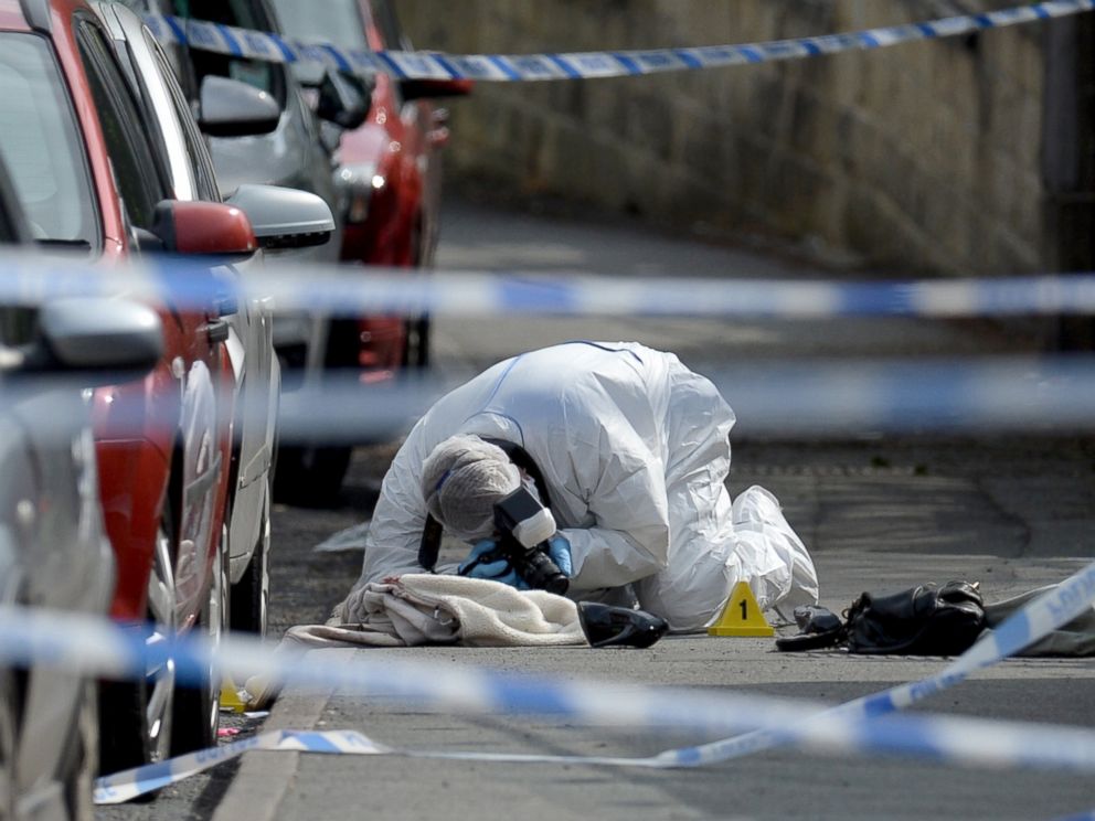 PHOTO: A police forensic officer works at the scene where a coat, shoe and handbag lie on the pavement outside the library in Birstall where Labour MP Jo Cox was shot, June 16, 2016.