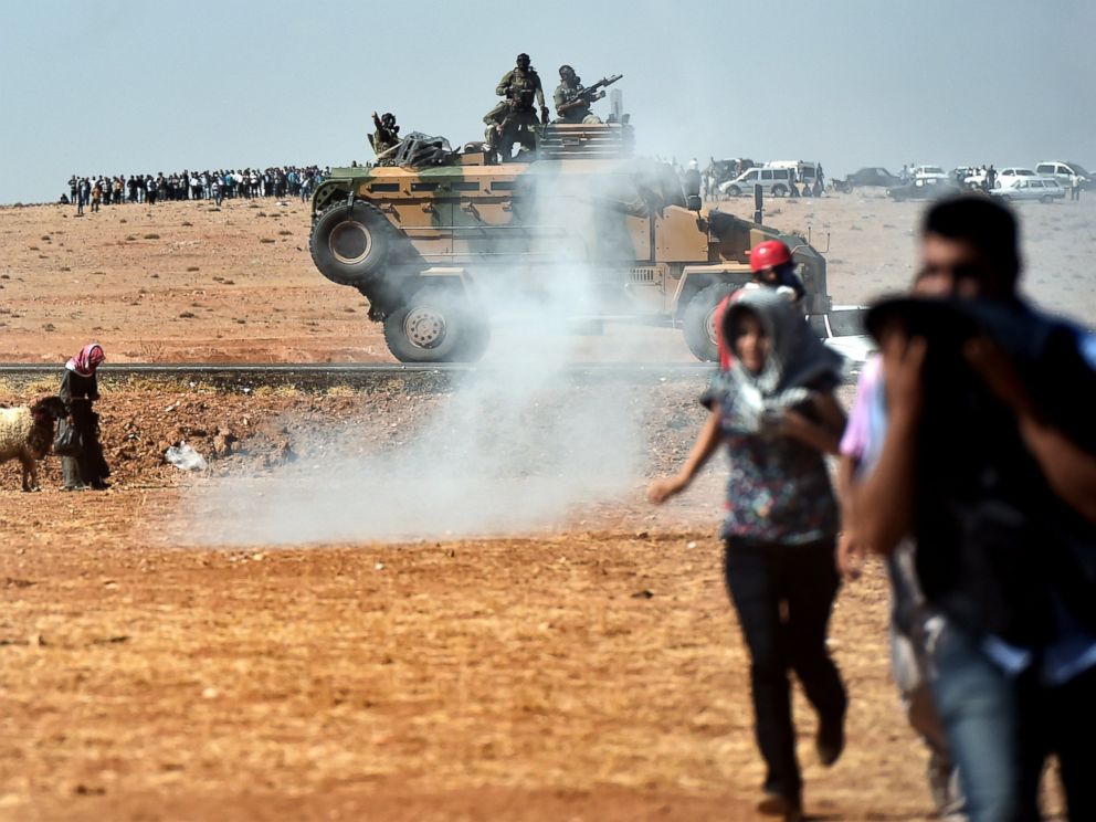 PHOTO: Kurdish people run away from tear gas as Turkish army tries to remove them from the Turkish-Syrian border area near the Syrian town known as Kobani by the Kurds, in the southeastern town of Suruc, Turkey, Oct. 7, 2014.