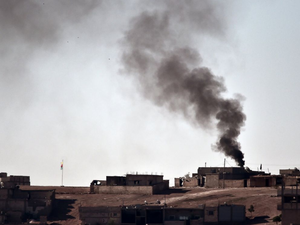 PHOTO: Smoke rises from the central part of the Syrian town of Ain al-Arab, known as Kobani by the Kurds, as seen from the Turkish-Syrian border, as a Kurdish flag waves during heavy fighting, in the southeastern town of Suruc, Turkey, Oct. 7, 2014.
