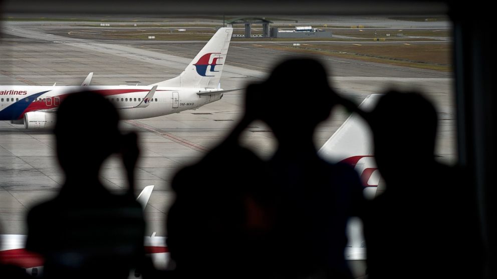 PHOTO: Malaysian children are silhouetted as they watch a Malaysia Airlines plane taxi on the runway at Kuala Lumpur International Airport in Sepang, March 17, 2014.