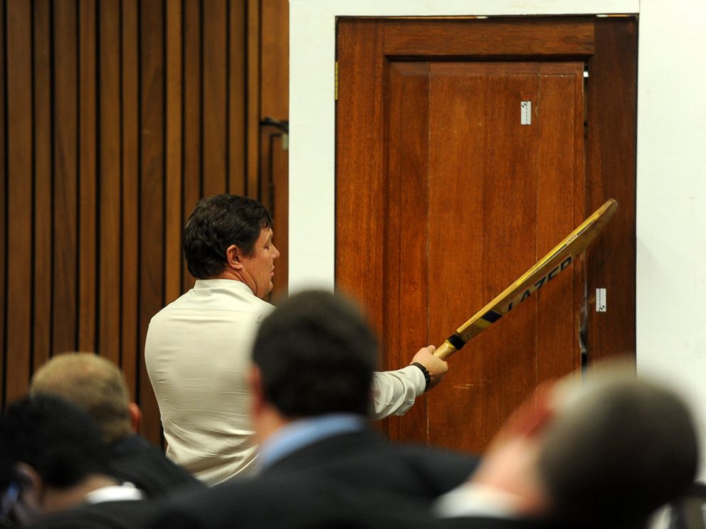 PHOTO: Forensic investigator Johannes Vermeulen takes part in the reconstruction of hitting a door with a cricket bat during the trial of Oscar Pistorius in Pretoria, South Africa on March 12, 2014.