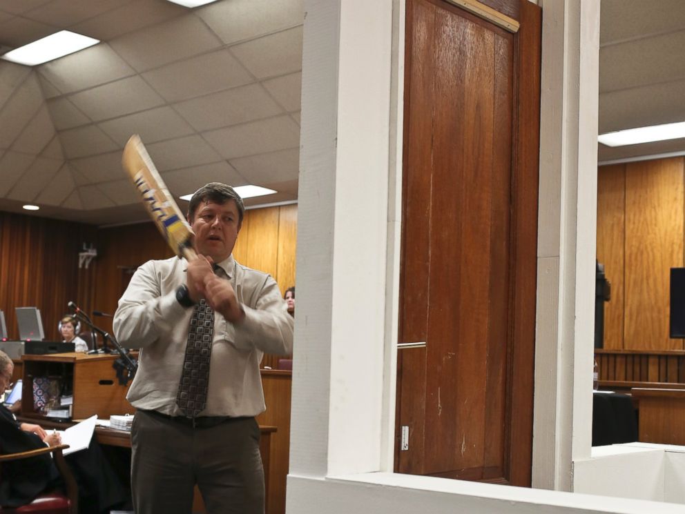 PHOTO: Forensic investigator Johannes Vermeulen takes part in the reconstruction of hitting a door with a cricket bat during the trial of Oscar Pistorius in Pretoria, South Africa on March 12, 2014.
