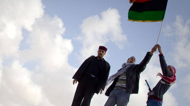 Libyan men celebrates on a destroyed tank belonging to the forces of Moammar Gadhafi in the outskirts of Benghazi, eastern Libya, Sunday, March 20, 2011. The tanks were destroyed earlier by U.S. and allied airstrikes.