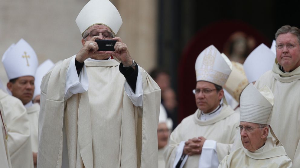 PHOTO: A bishop uses his mobile phone to take photographs as he arrives for the canonization ceremony of Popes John XXIII and John Paul II to start in St. Peters Square at the Vatican April 27, 2014.