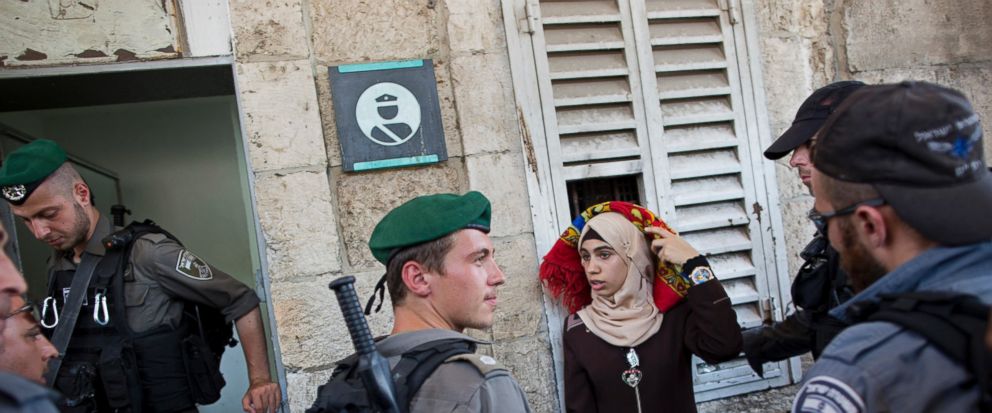 Israeli border police officers stop a Palestinian woman for a security check as Palestinians gather for prayer at the Lions Gate, following an appeal from clerics for Muslims to pray in the streets instead of the Al-Aqsa Mosque compound, in Jerusale