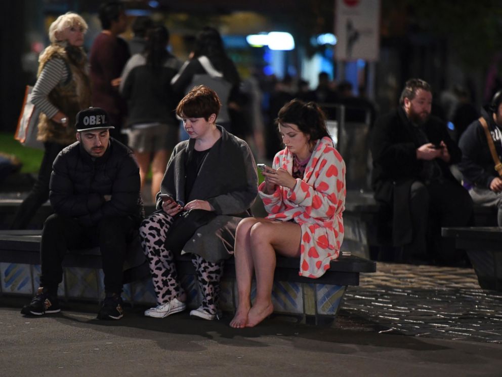 PHOTO: People evacuated from buildings along Dixon Street check their mobile phones while sitting on a bench in Wellington, New Zealand, after a 6.6 earthquake, Nov. 14, 2016.