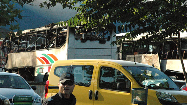 PHOTO: Bulgarian policeman is seen in front of destroyed buses at Burgas Airport, outside the Black Sea city of Burgas, Bulgaria, Wednesday, July 18, 2012.