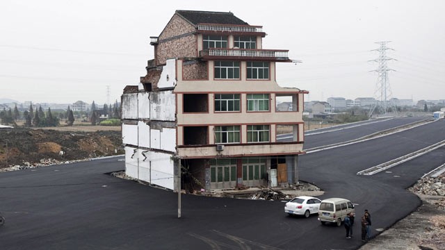 PHOTO: In this Nov. 22, 2012 file photo, people stand near a house sitting in the middle of a new main road on the outskirts of Wenling city in east China's Zhejiang province.