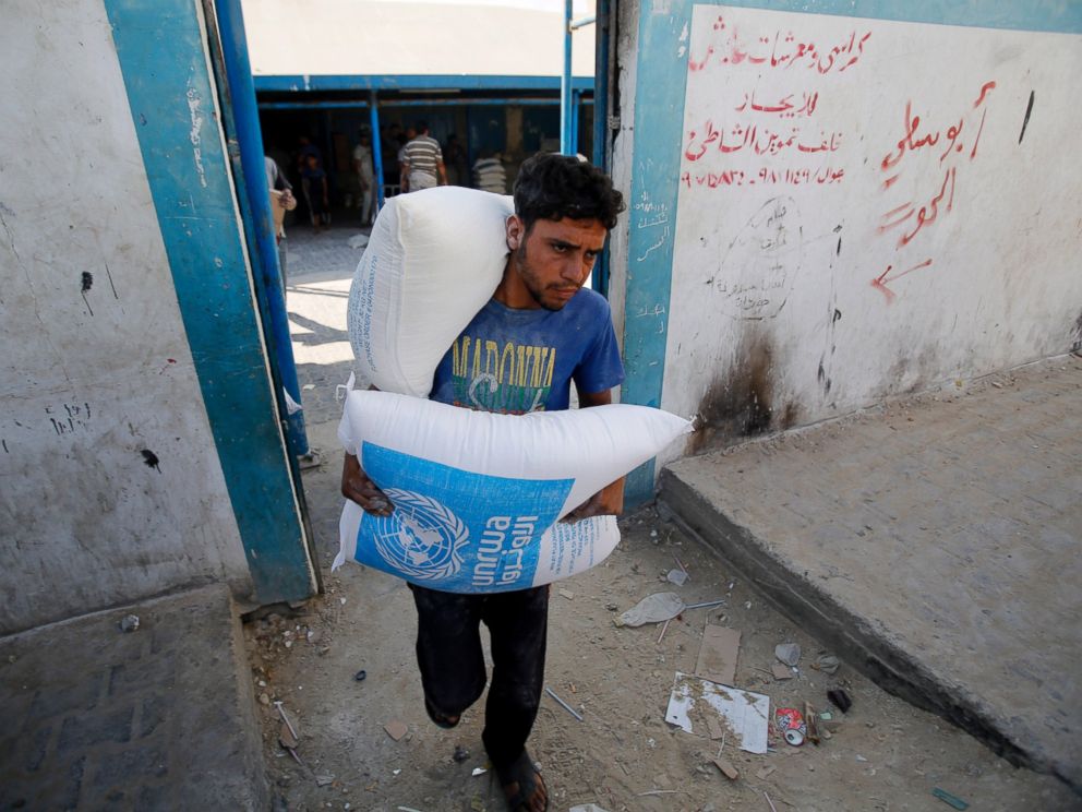 PHOTO: A Palestinian carries bags of flour at a United Nations food aid distribution center, in Shati refugee camp in Gaza City, Aug. 6, 2014.