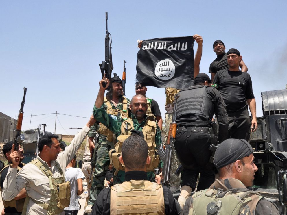 PHOTO: Iraqi security forces hold up a flag of the the jihadist group ISIS that they captured during an operation to regain control of Dallah Abbas, 35 miles outside of Baghdad, Iraq on Jun 28, 2014.