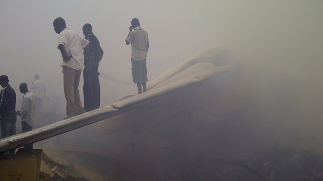 PHOTO: Onlookers stand on the tail wing of a crashed passenger plane in a neighborhood just north of Murtala Muhammed International Airport, in Lagos, Nigeria, Sunday, June 3, 2012.