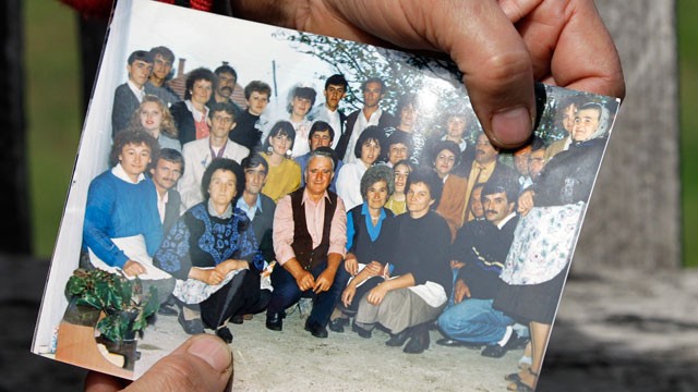 PHOTO: A woman points to Ljubisa Bogdanovic, top row third right, with her left thumb in a group picture in the village of Velika Ivanca, Serbia, April 9, 2013.