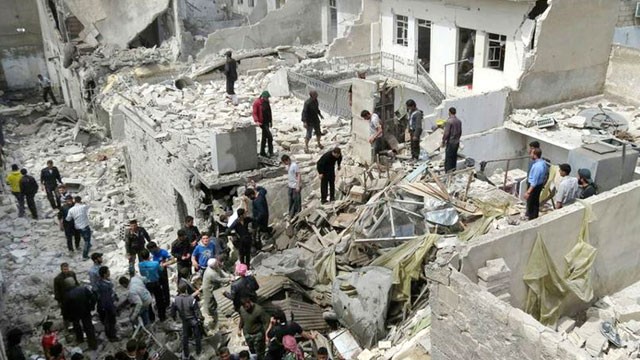 PHOTO: Syrian citizens stand on rubble of destroyed houses that were damaged by Syrian forces airstrike, in Aleppo, Syria, April 15, 2013.