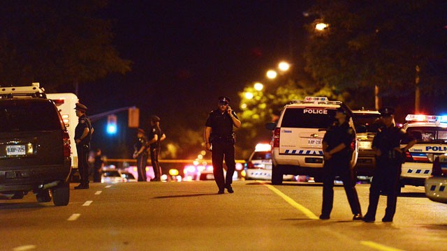 PHOTO:&nbsp;Police stand on guard on Morningside Ave. in Toronto early Tuesday, July 17, 2012, near the scene of a shooting where at least 19 people were injured and twowere killed at a house party late Monday, July 16.