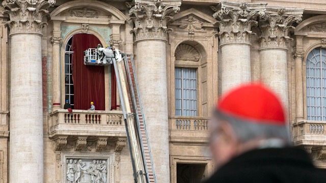 PHOTO: Workers use a crane to place a burgundy curtain around the door frame of the balcony on the front of St. Peter's Basilica where the newly elected pope will make his first appearance at the Vatican, March 11, 2013.