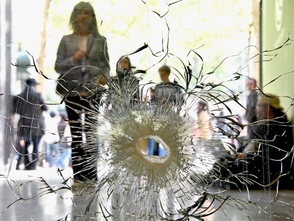 PHOTO: People look at a bullet hole in a window near to the Marks and Spencer on the Champs Elysees in Paris following the shooting of a police officer on April 21, 2017.