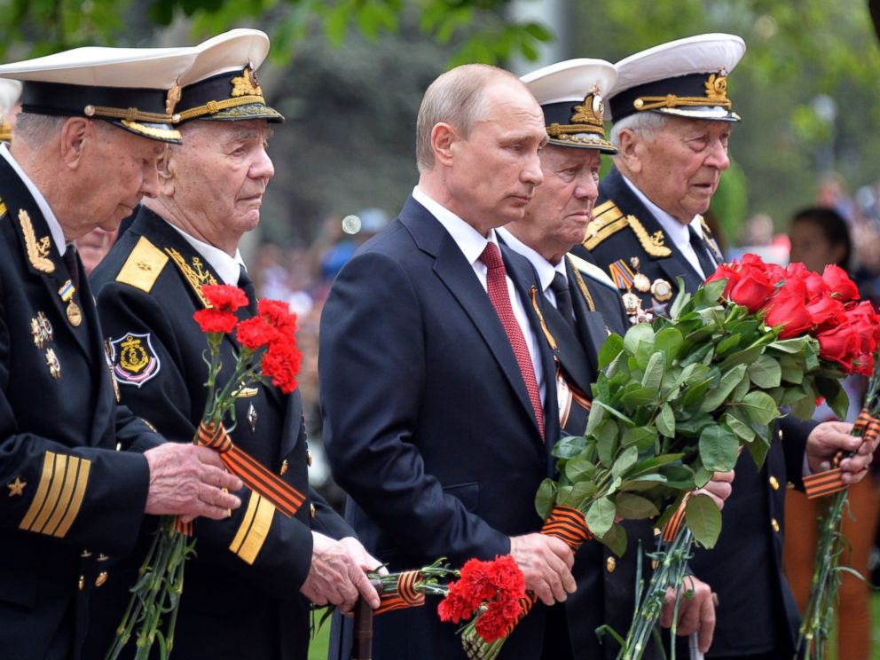 PHOTO: Russias President Vladimir Putin, center, and World War II veterans law flowers at a war memorial during their visit to the Crimean port of Sevastopo, May 9, 2014.