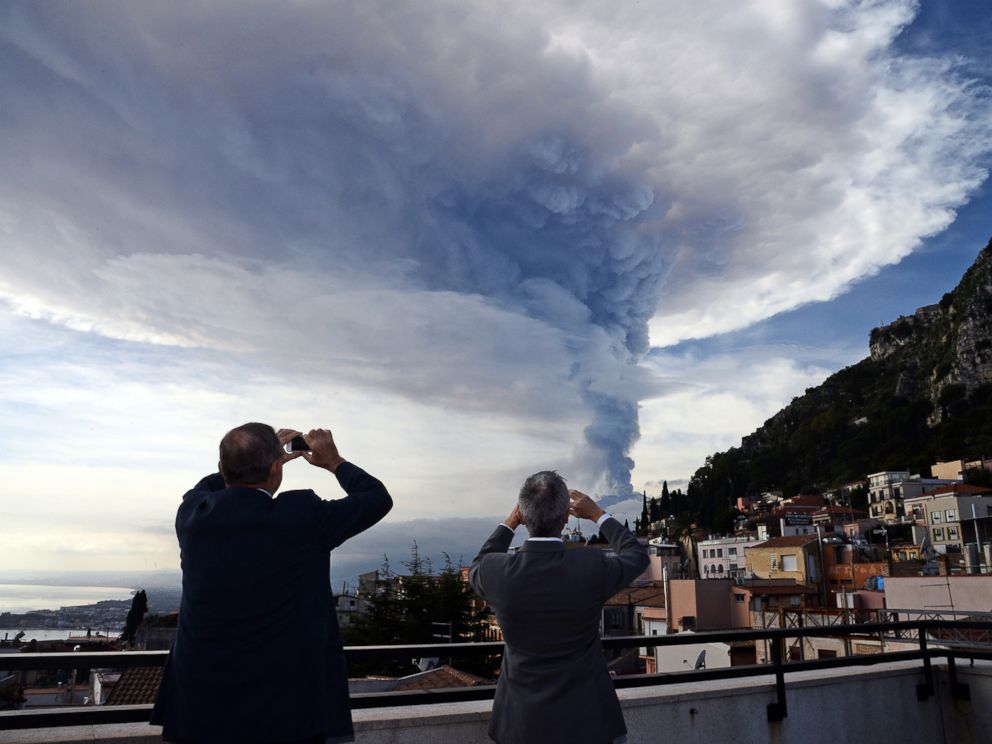 PHOTO: People take pictures of the smoke rising over the city of Taormina during an eruption of the Mount Etna, one of the most active volcanoes in the world, near Catania, Dec. 4, 2015.
