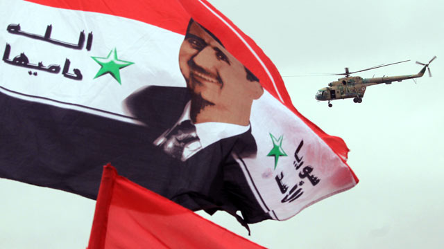 PHOTO: A Syrian army helicopter hovers above a national flag bearing a portrait of Syrian President Bashar al-Assad, in this Jan. 11, 2012 file photo.