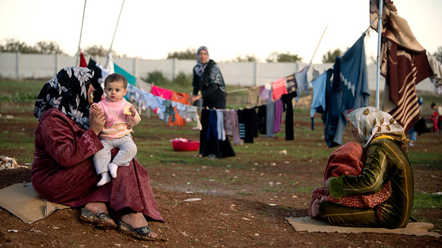 PHOTO: Mothers and their children sit among their washing in a refugee camp on the border between Syria and Turkey near the northern city of Azaz on Dec. 5, 2012.