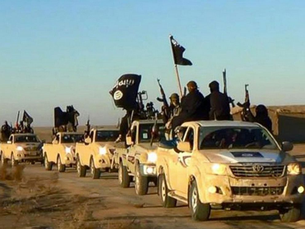 PHOTO: In this undated file photo released online in the summer of 2014 which has been verified and is consistent with other AP reporting, ISIS militants hold up their weapons and wave flags in a convoy on a road leading to Iraq, in Raqqa, Syria.