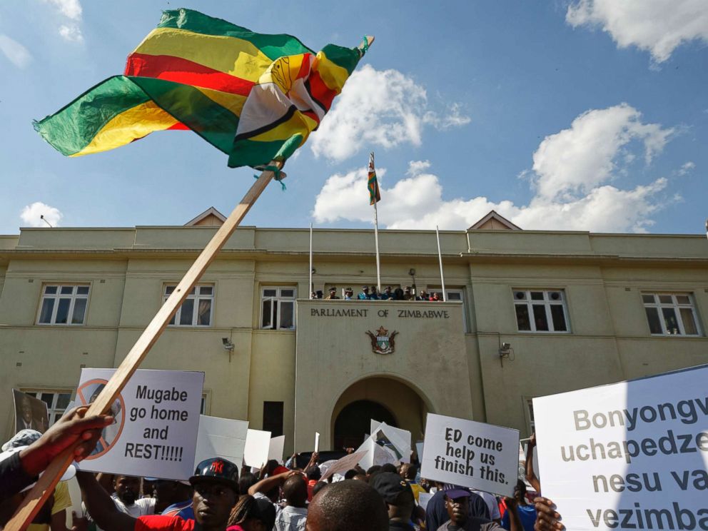 PHOTO: Protesters calling for the impeachment of President Robert Mugabe brandish a national flag as they demonstrate outside the parliament building in Harare, Zimbabwe, Nov. 21, 2017.