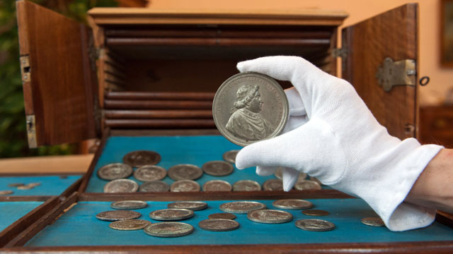 PHOTO: A hand holds a coin with Cardinal Clemens XI at the State Library in Passau, Germany, Dec. 7, 2011.