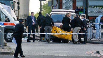 Police officers carry equipment while investigating a crime scene of an apparent attack that left one man confirmed dead and two people wounded near Woolwich barracks in London, May 22, 2013.