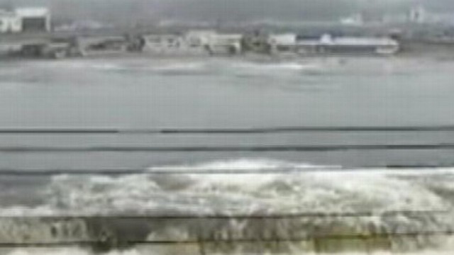 VIDEO: Watch as the powerful wave breaches floodgates, washing away a car.
