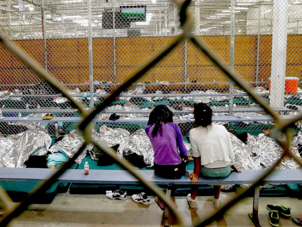 PHOTO: Two young girls watch a World Cup soccer from their holding area where hundreds of immigrant children are being processed at the U.S. Customs and Border Protection Nogales Placement Center, June 18, 2014, in Nogales, Ariz.