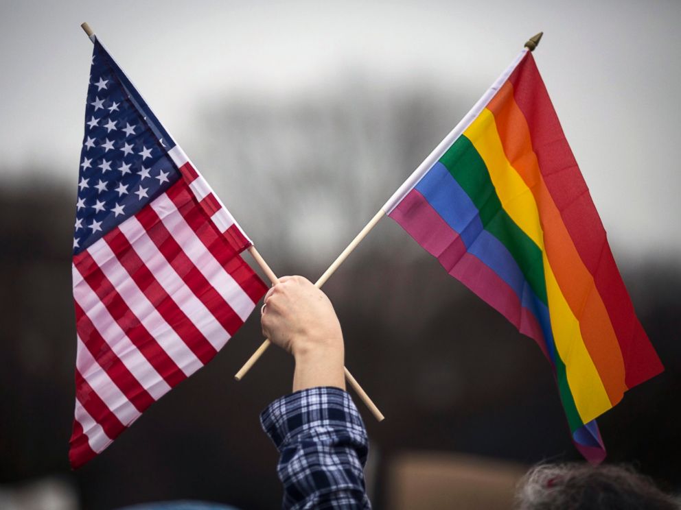 PHOTO: A participant holds both the U.S. national flag (L) and the LGBT communitys symbolic Rainbow flag (R) as people arrive on the mall for the Million Woman March in Washington, D.C., Jan. 21, 2017. 