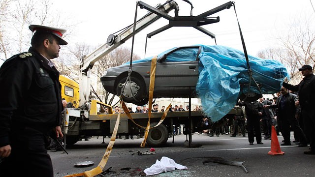PHOTO: People gather around a car as it is removed by a mobile crane in Tehran, Iran, Jan. 11, 2012.