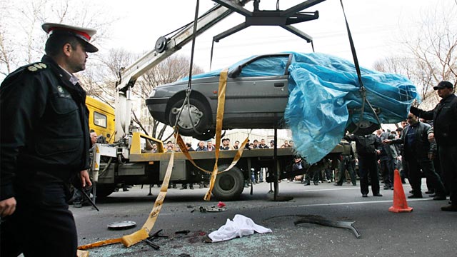 PHOTO: People gather around a car as it is removed by a mobile crane in Tehran, Iran, Jan. 11, 2012.