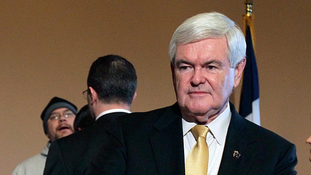PHOTO: Newt Gingrich, pauses as an unidentified protester is confronted by security during a news conference.